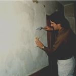 Peter applies a final coat of lime and gauging plaster to the wall following repairs. He is using a trowel and damp sponge to blend the repair areas into the original wall area.